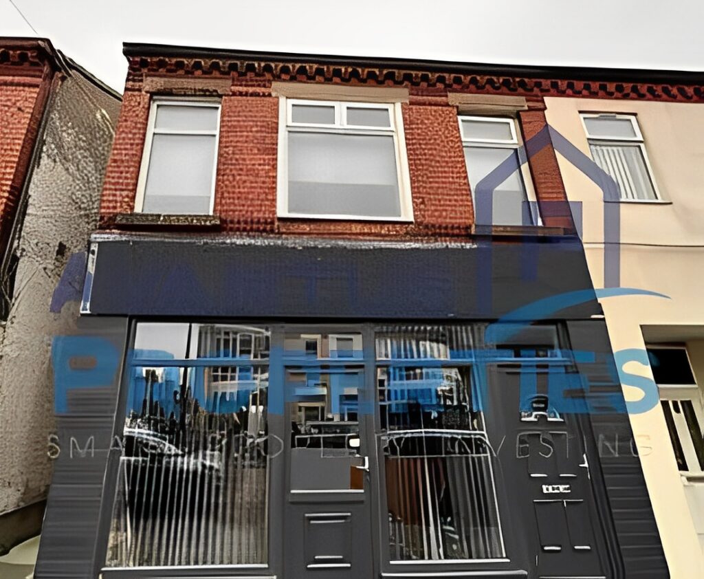 Two-storey red brick commercial building with black-painted storefront and large windows.